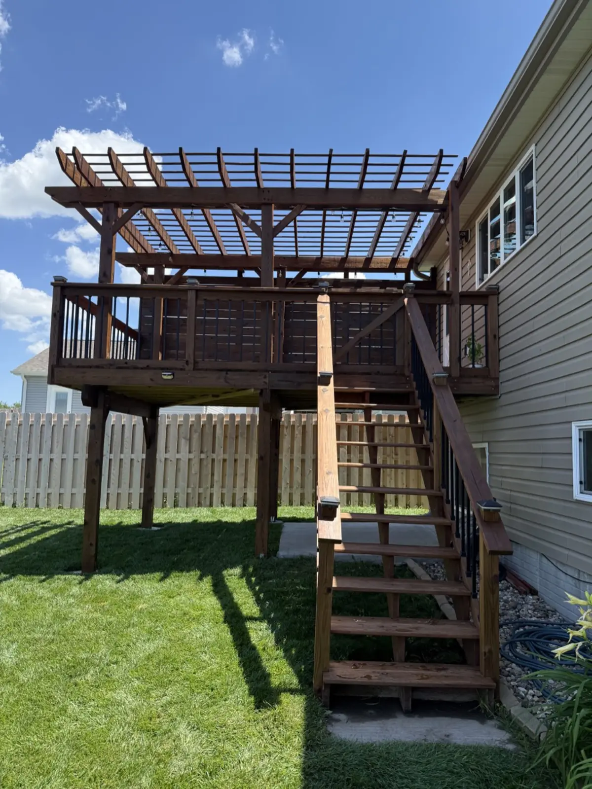 Stained deck stairs and railings leading up to a pergola